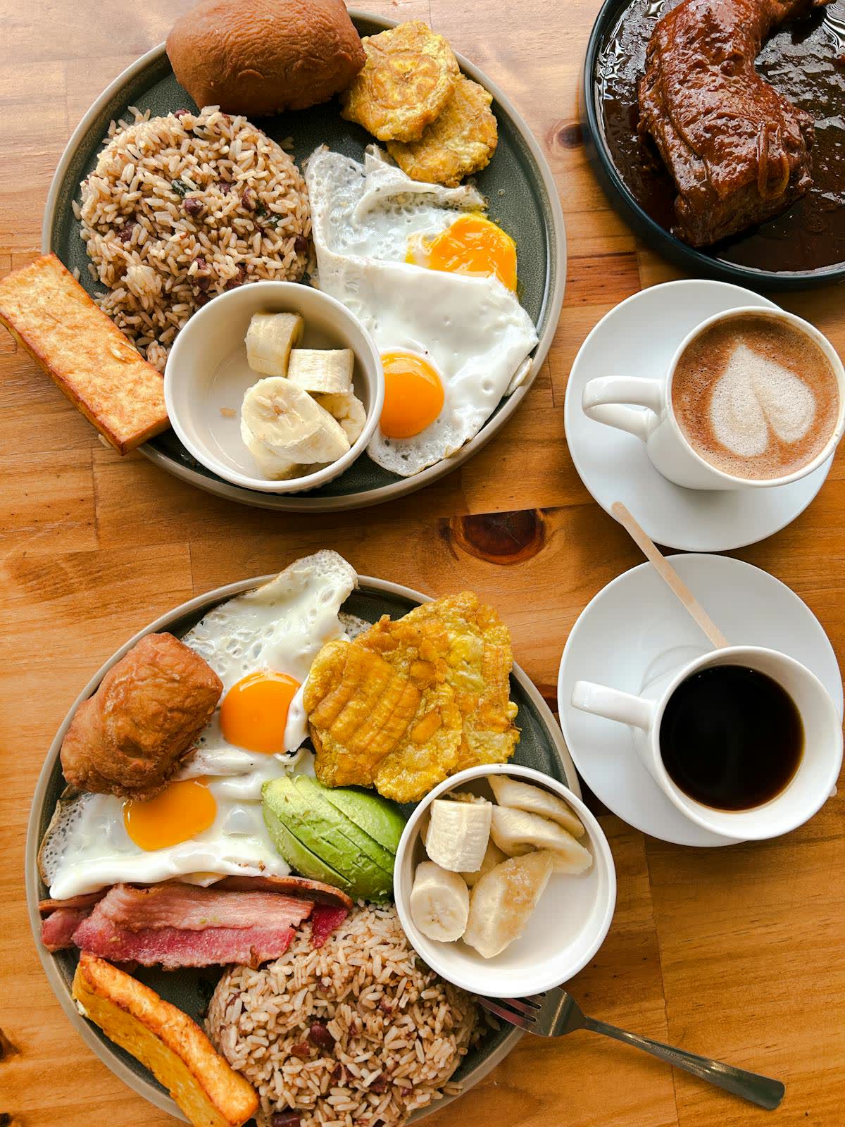 Desayuno típico costarricense con huevos, arroz, plátanos y café en mesa de madera — restaurante familiar en La Fortuna